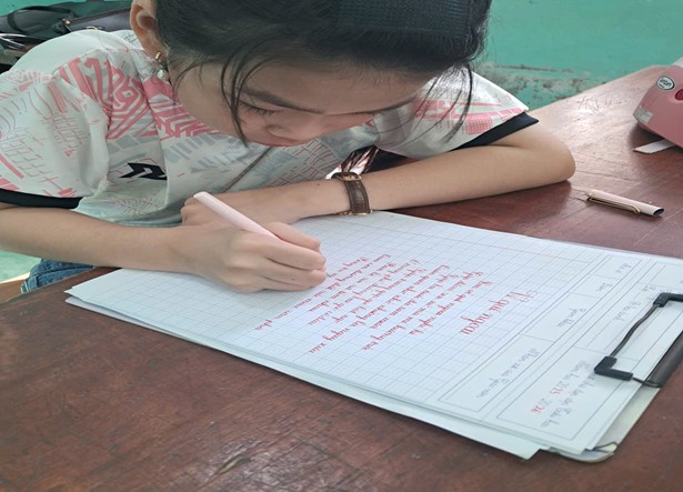 Em Phạm Ha Na đang cắm cúi luyện chữ.